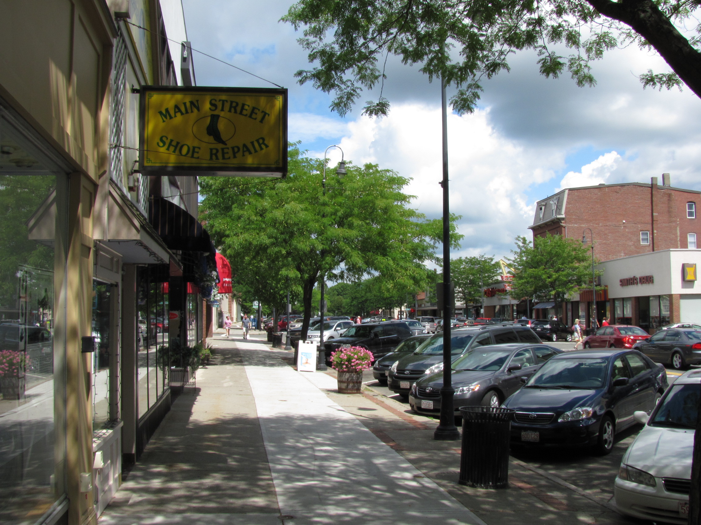 Main Street in Wakefield, Massachusetts, photographed in July 2010, with downtown storefronts, sidewalks, street trees, and parked cars.